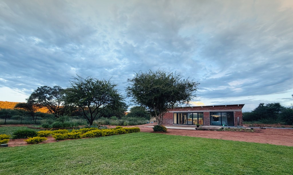 Masimo Cabins — brick cabin with glass front, lawn and hills at golden hour